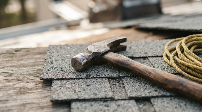 A roofing hammer and coiled rope resting on shingles